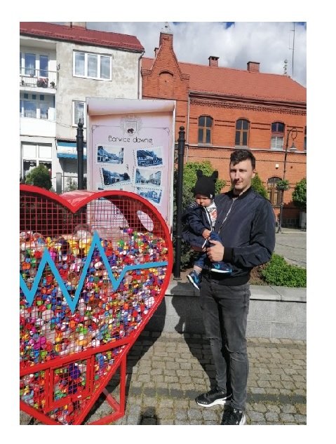 Bartosz Brzeczka z synkiem Frankiem na tle serca z nakrętkami