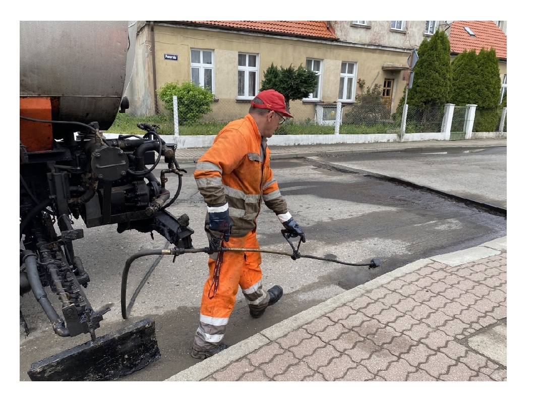 Drogowiec nakładający warstwę ścieralną asfaltu na ulicy Łąkowej