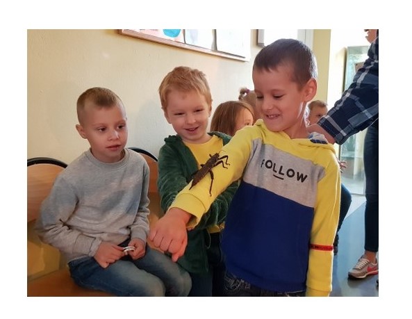 3 chłopców - jeden z nich ma rękawie wielkiego owada