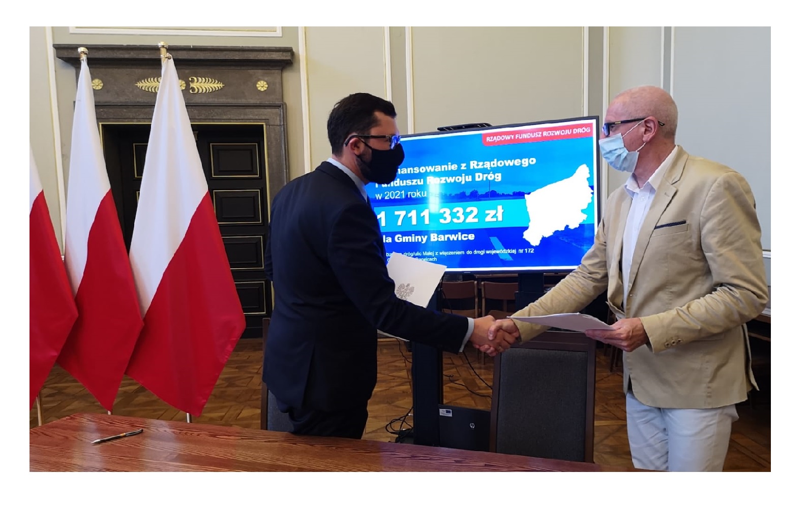 Burmistrz ściska rękę z wicewojewodą w trakcie przekazania umowy