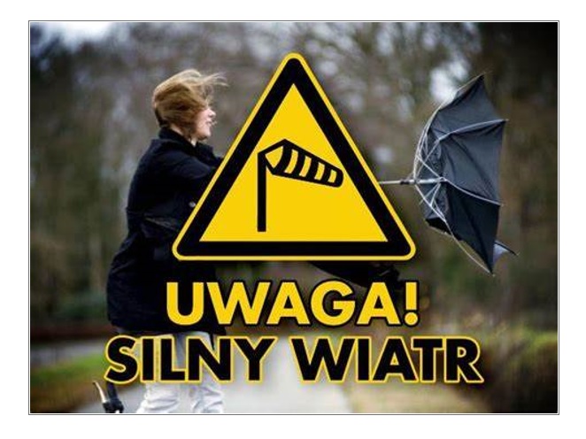 Znak silny wiatr, w tle kobieta z parasolką walcząca z podmuchem wiatru