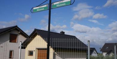 Widok na tabliczkę kierunkową z nawa ulic w tle dom jednorodzinny