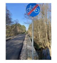 Ścieżka rowerowa biegnąca przez stary wiadukt kolejowy. Na pierwszym planie znak - koniec ścieżki rowerowej. 